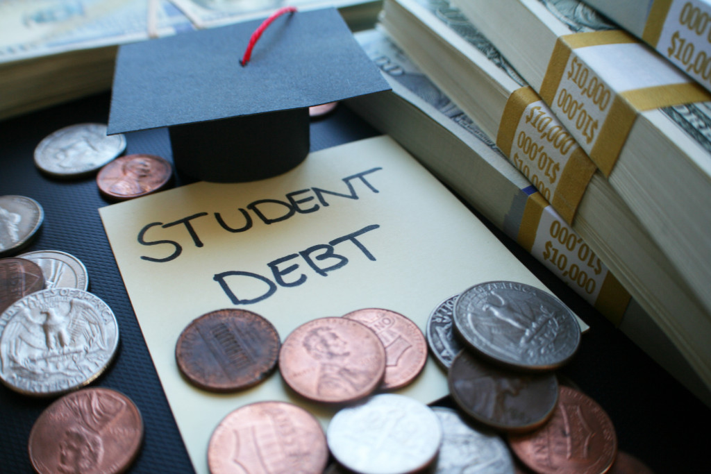 student debt concept with coins and small grad cap